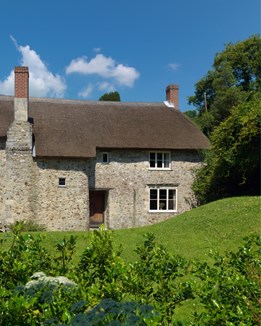 A thatched stone cottage with green gardens