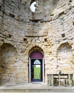 Outdoor seating area behind a rustic folly