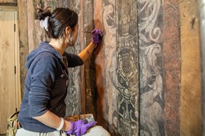 Woman painting intricate wall paintings at Calverley Old Hall