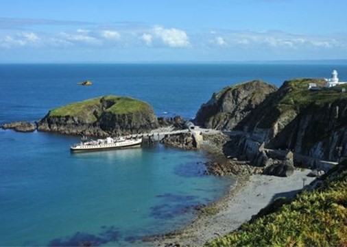 An island harbour with cliffs, a small beach and view out to sea