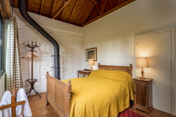 A double bed with yellow sheets in a room with white walls