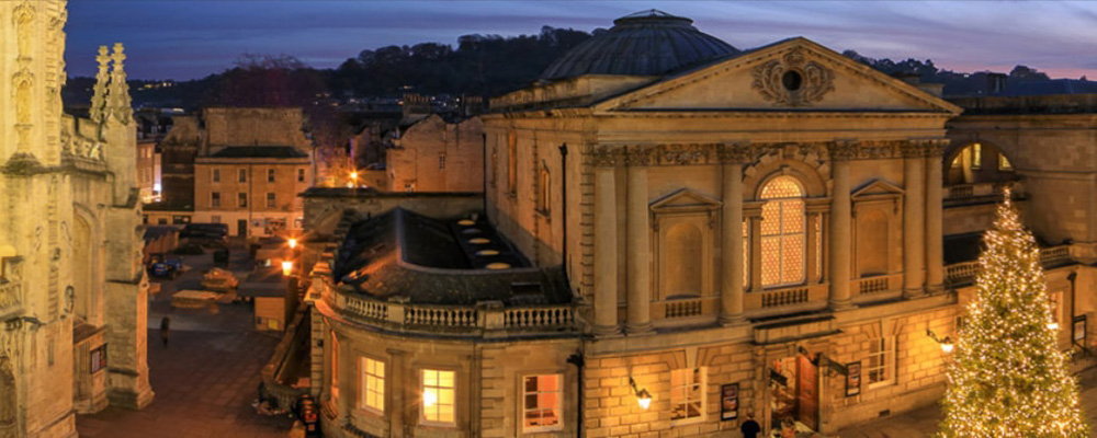 View of Bath Spa and the cathedral in the evening with a lit Christmas tree 