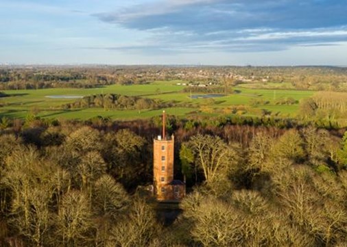 A red brick tower surrounded by trees and fields